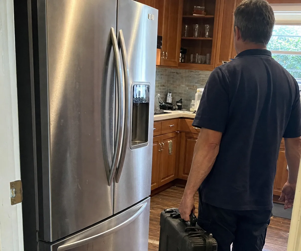 Right-hand crop of an older kitchen with timber cabinets and a technician arriving with equipment