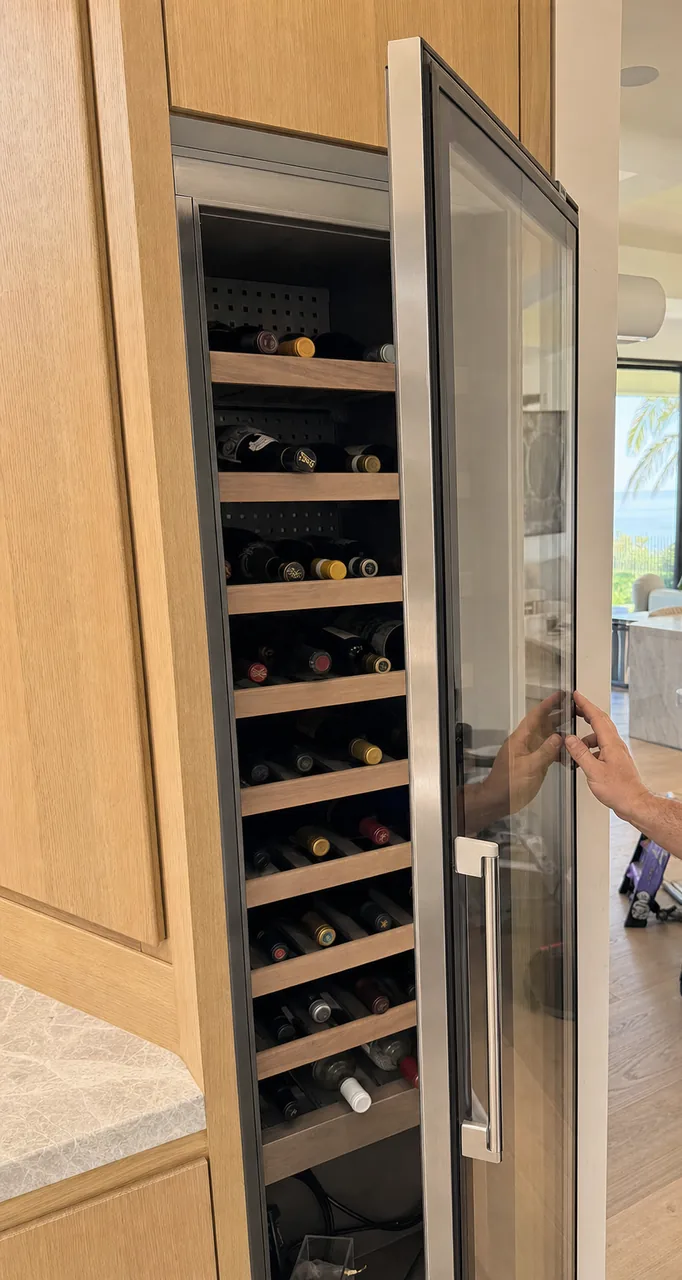 Narrow crop of a wine column built into a run of pale timber cabinets